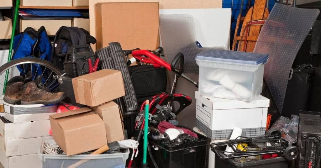 garage-cleanout-tips pile of boots boxes containers and other junk in garage before cleanout