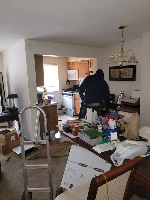 cluttered disgusting Norristown PA apartment full of trash with man working to clean up unwanted items