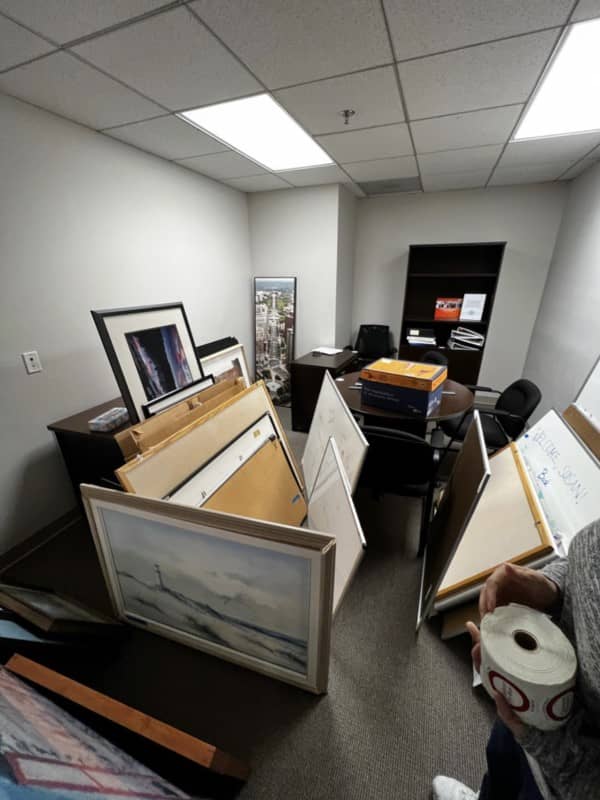 cluttered office storage closet with old white boards picture frames and boxes