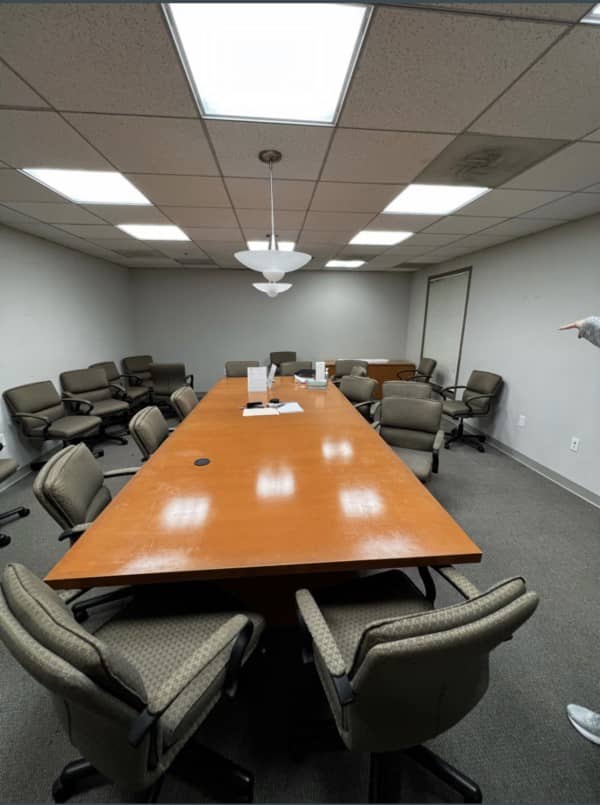 large conference room table and scattered chairs in messy conference room