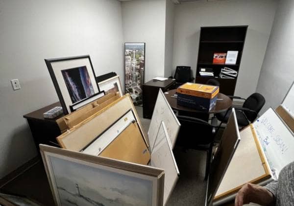cluttered office storage closet with old white boards picture frames and boxes