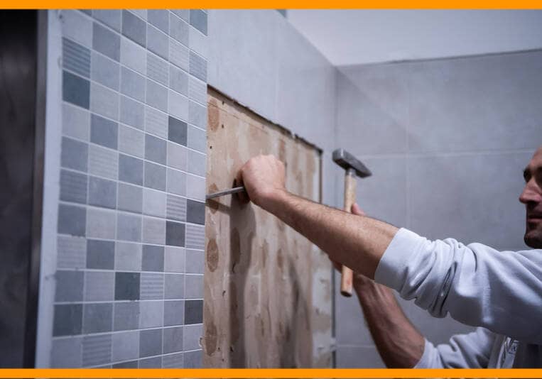professional worker remove demolish old tiles in a bathroom with hammer and chisel